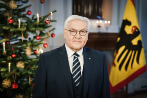 Foto von Frank-Walter Steinmeier in einem dunklen Anzug, im Hintergrung ein geschmückter Weihnachtsbaum und eine Fahne mit dem Bundesadler darauf