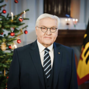 Foto von Frank-Walter Steinmeier in einem dunklen Anzug, im Hintergrung ein geschmückter Weihnachtsbaum und eine Fahne mit dem Bundesadler darauf